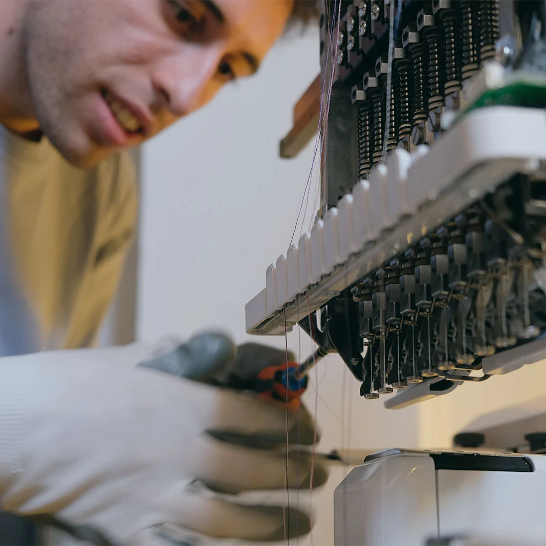 Alessio Solazzi mentre esegue una manutenzione su una ricamatrice industriale