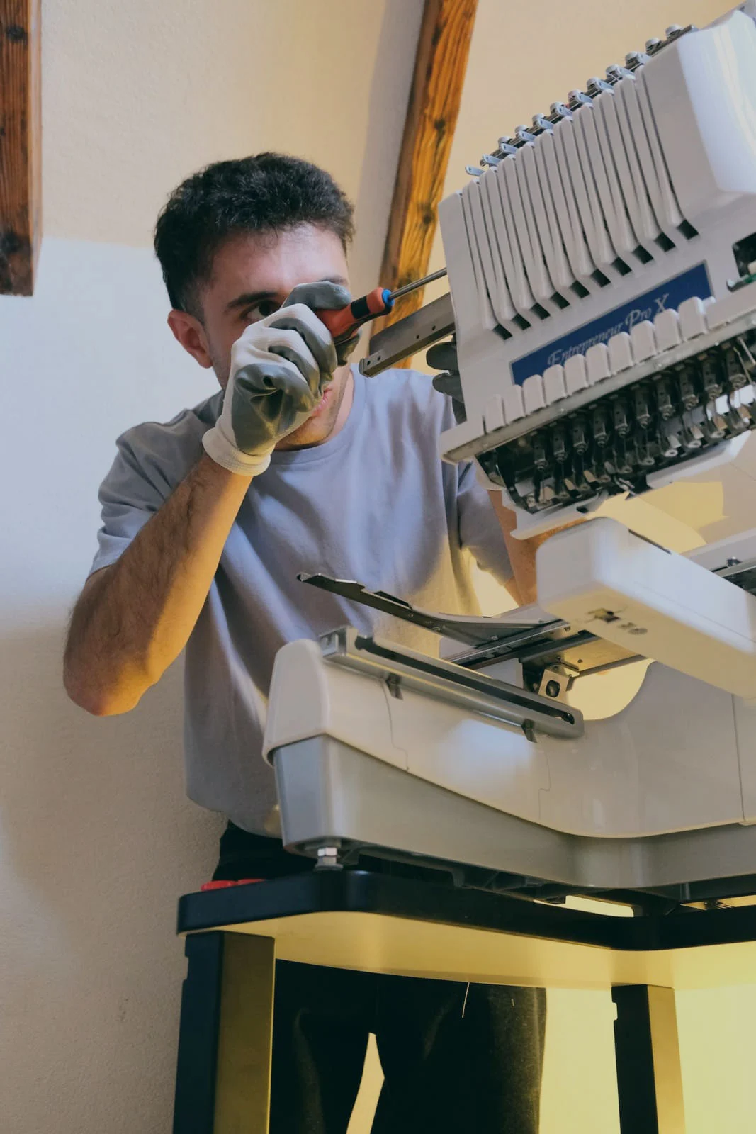 Alessio Solazzi mentre esegue una manutenzione tecnica su una ricamatrice